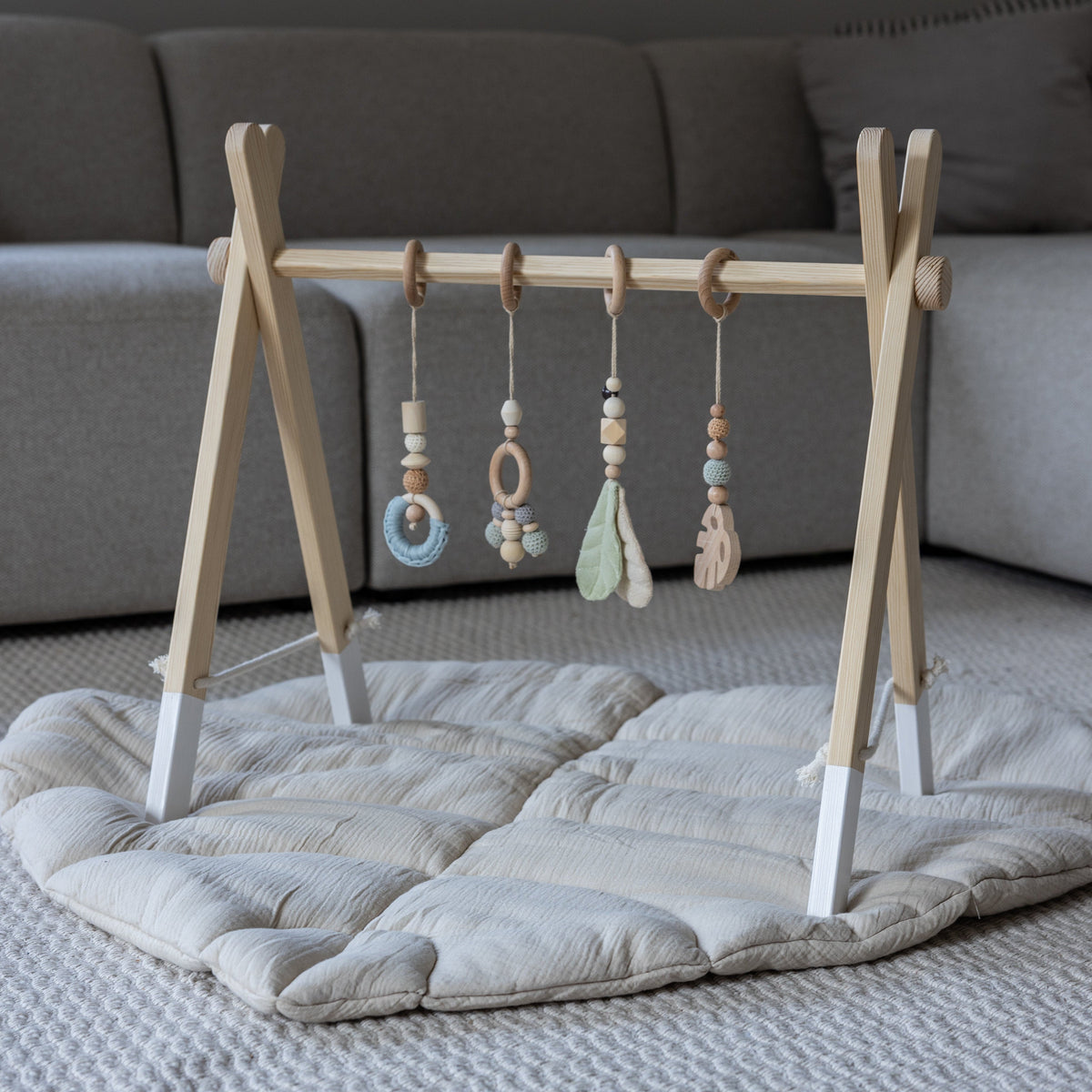 Klappbarer Zwergensache Spielbogen aus Holz mit Vintage-Mint-Anhängern auf einer Blattdecke im Wohnzimmer